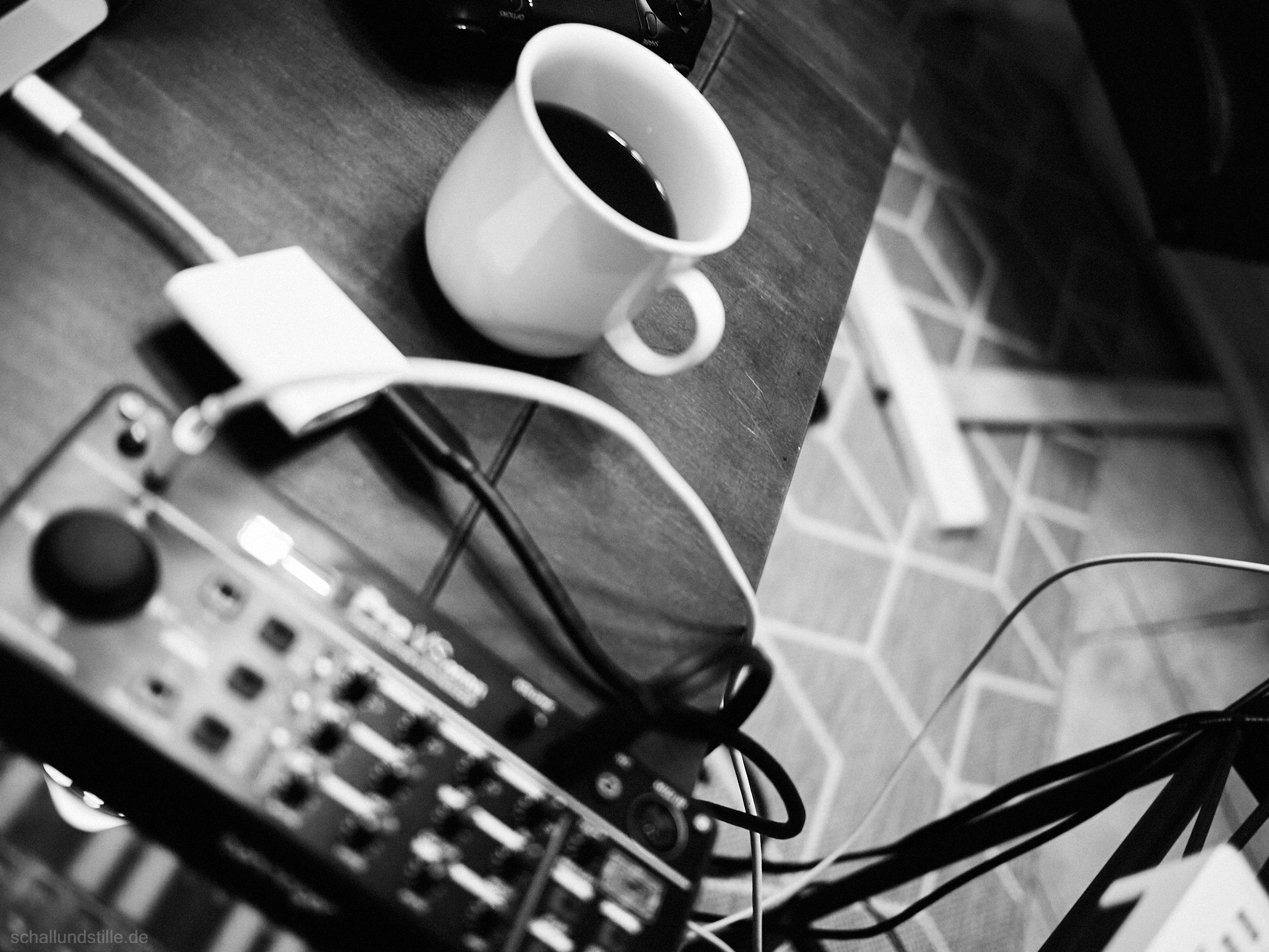black and white picture of a Behringer Pro VS Mini synthesizer (unsharp) in the foreground and a cup of coffee in the background
