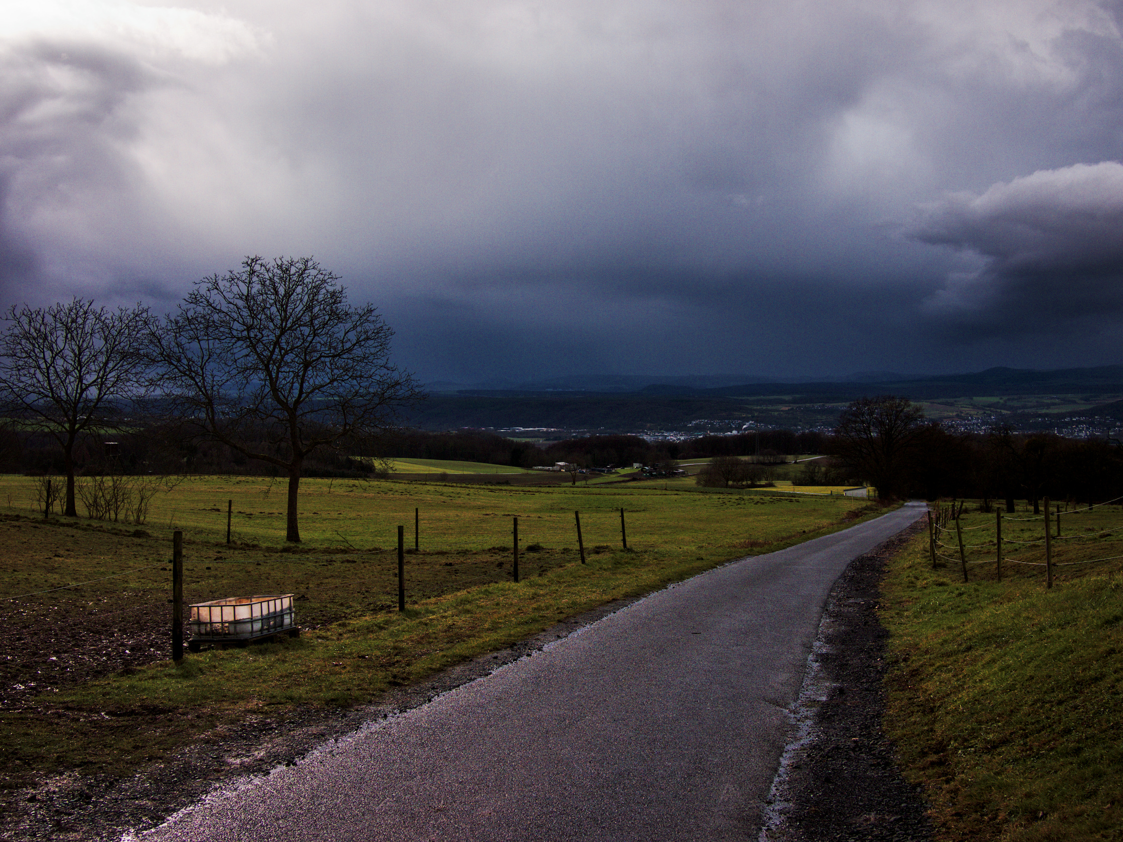 A country road leading into a valley in stormy weather.