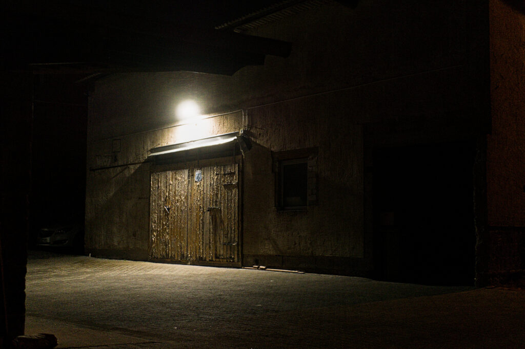 A outbuilding at night, illuminated by a single LED lamp.